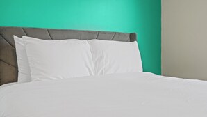 Una cama con cabecera tapizada en gris y ropa de cama blanca.
