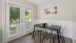 Un comedor con una mesa y sillas, un cuadro en la pared y vistas al exterior.