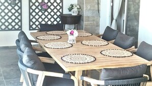A dining area with a wooden table, black cushioned chairs, a chandelier, and a decorative wall panel. - Charming 3-bedroom Penthouse with AC, WiFi in lovely Oroklini (Oroklini)