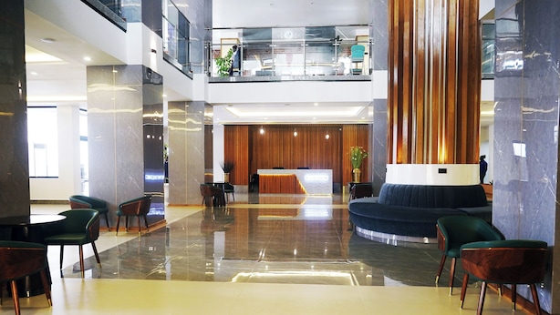 A spacious lobby with a reception desk, seating area, and a high ceiling with a glass railing.