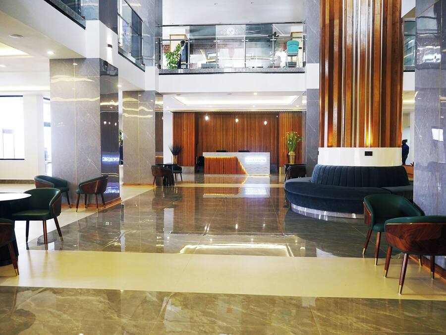 A spacious lobby with a reception desk, seating area, and a high ceiling with a glass railing.