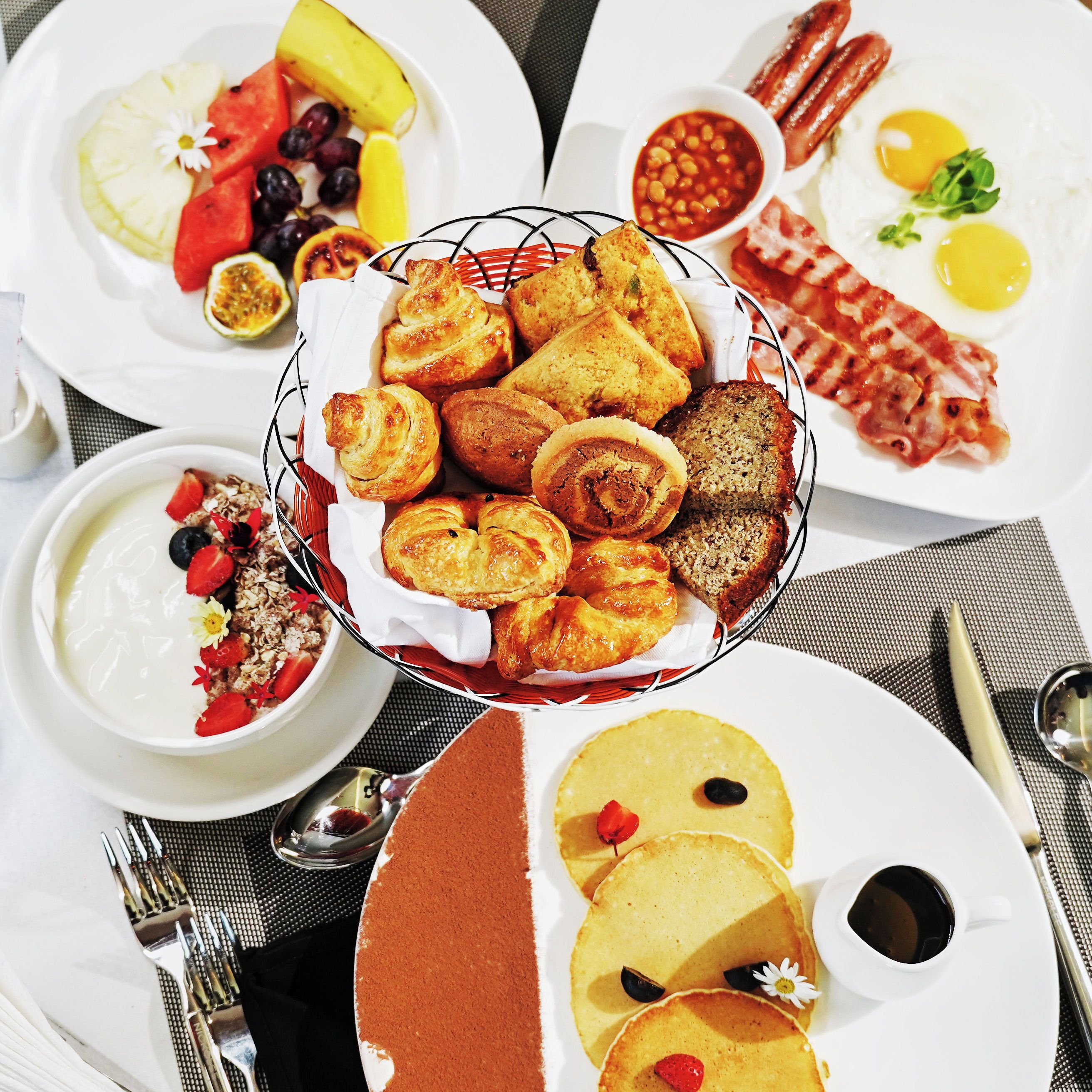 A breakfast spread with various dishes including pastries, eggs, and fruits.