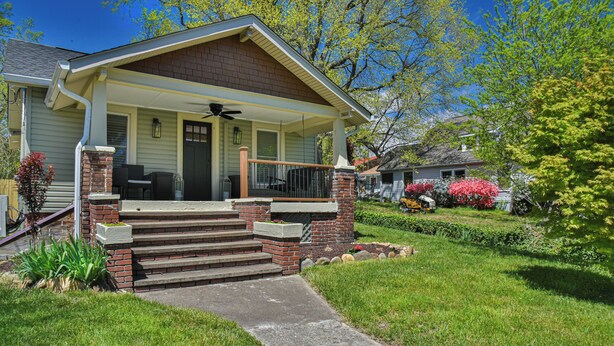 A two-story house with a front porch, brick steps, and a small garden. - Les Petit Maison (Black Mountain)