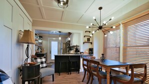 A modern kitchen with a central island, wooden dining table, and bar stools. - Les Petit Maison (Black Mountain)
