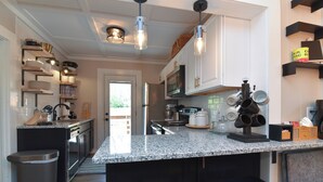 A modern kitchen with granite countertops, stainless steel appliances, and pendant lighting. - Les Petit Maison (Black Mountain)