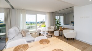 Een moderne woonkamer met een grote bank, een eettafel en uitzicht op een balkon.
