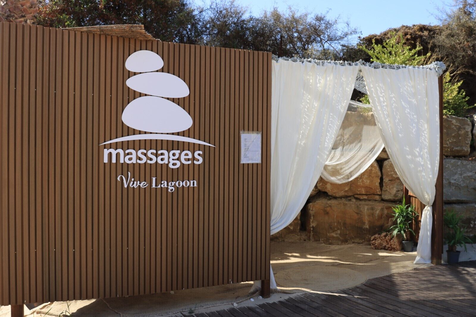 Une structure en bois portant le logo de « Massages Vive Lagoon ».