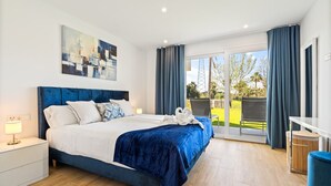 Une chambre à coucher moderne, dotée d’un grand lit, d’une table de chevet, d’un bureau et offrant une vue sur l’extérieur.