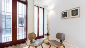 A room with two chairs, a small table, and a door with a view of the street. - GuestReady - Clérigos Tiles House (Porto)