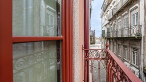 A narrow street with buildings on either side, featuring balconies with metal railings and a red door. - GuestReady - Clérigos Tiles House (Porto)