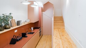 A modern kitchen with a wooden countertop, a sink, and a built-in oven. There is a staircase leading to another level. - GuestReady - Clérigos Tiles House (Porto)