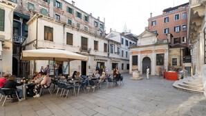 An outdoor cafe with tables and chairs, surrounded by historic buildings with architectural details.