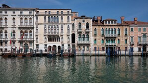 A row of historic buildings along a canal with water reflecting the architecture.