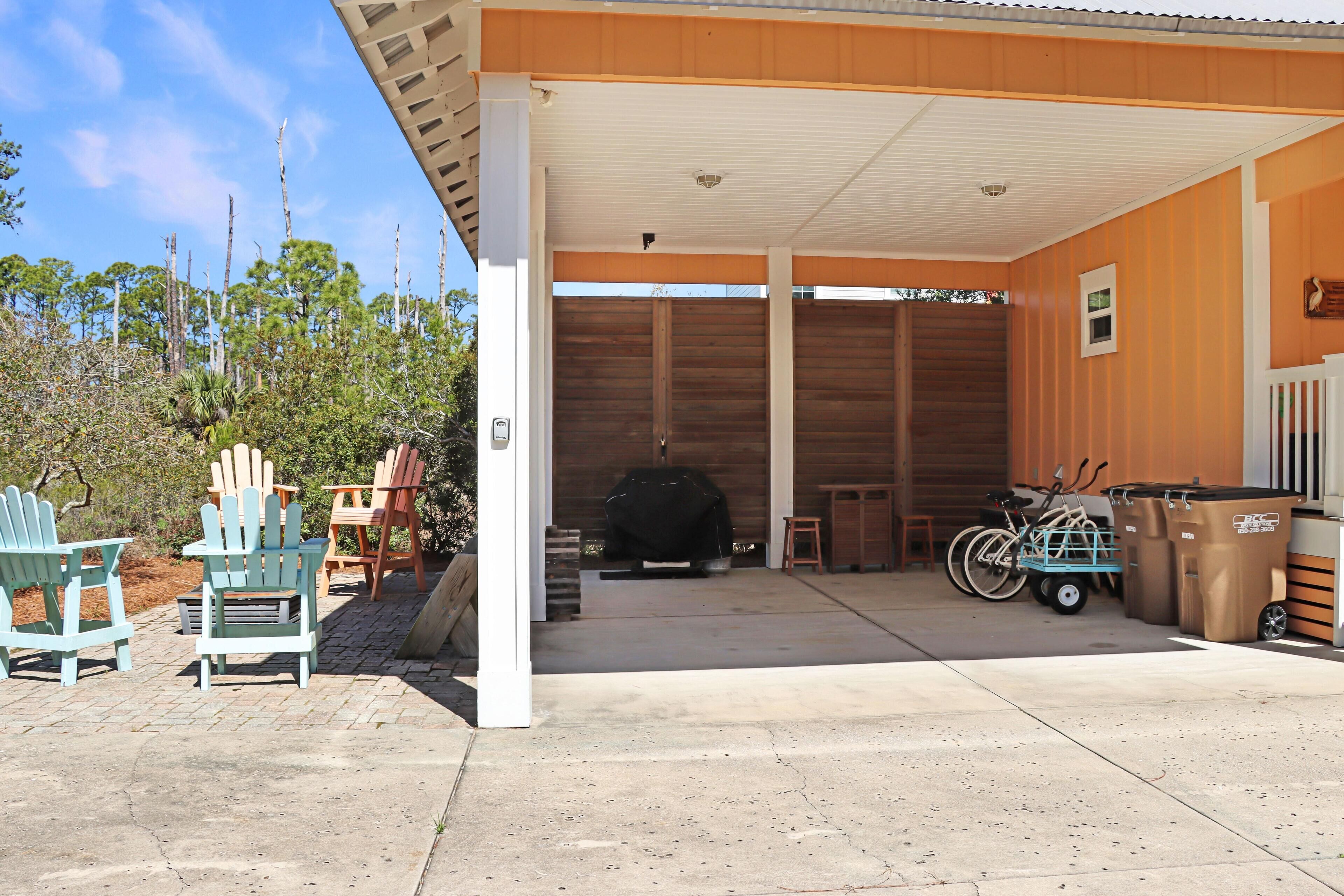 Un espace extérieur abrité comprenant un barbecue, un vélo et une poubelle.