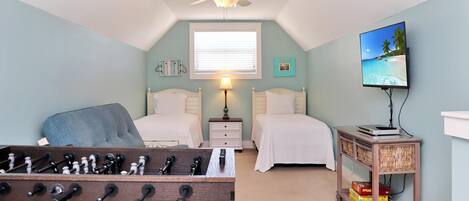 A bedroom with two beds, a ceiling fan, a TV, and a small table with a board game.