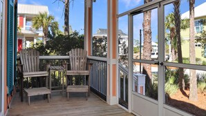 A covered outdoor area with wooden chairs and a table, overlooking a residential neighborhood with palm trees and houses.