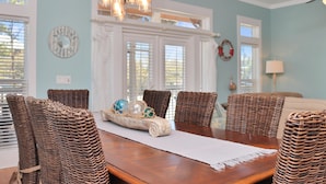 A dining area with a wooden table, wicker chairs, and a chandelier.