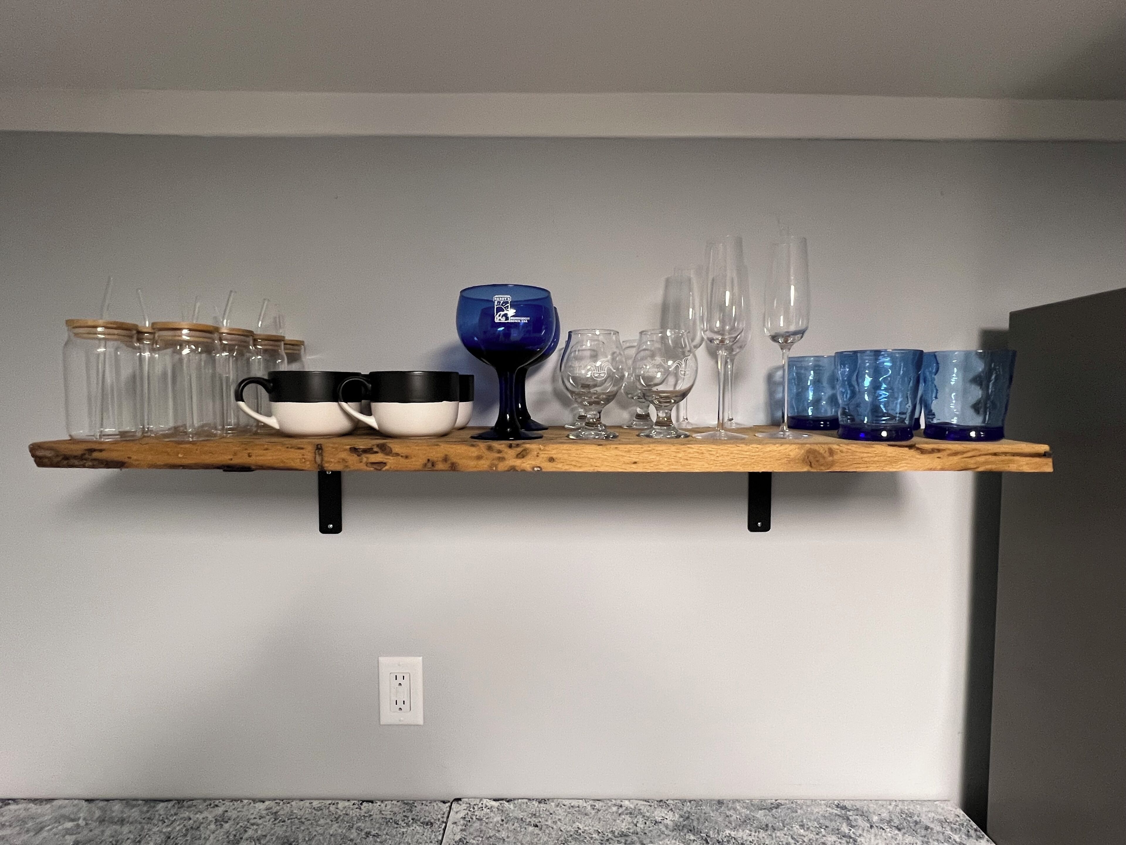A wooden shelf with various glassware and dishes.