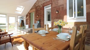 A dining area with a wooden table set for four, surrounded by wooden chairs. - 1 Deuchrie Cottages (Dunbar)