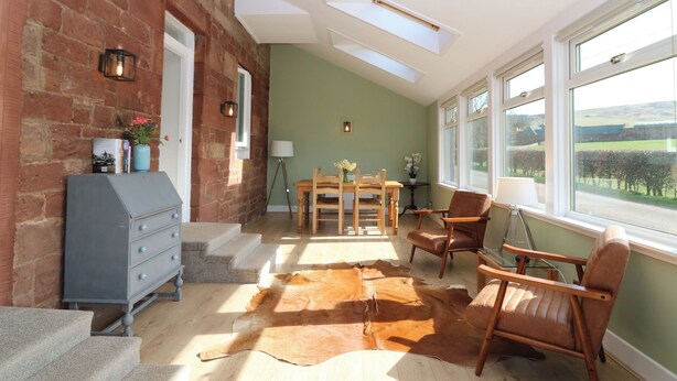 A dining area with a table, chairs, and a cowhide rug. - 1 Deuchrie Cottages (Dunbar)