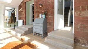 A spacious room with a high ceiling, a skylight, a staircase leading to another level, and a leather sofa. - 1 Deuchrie Cottages (Dunbar)
