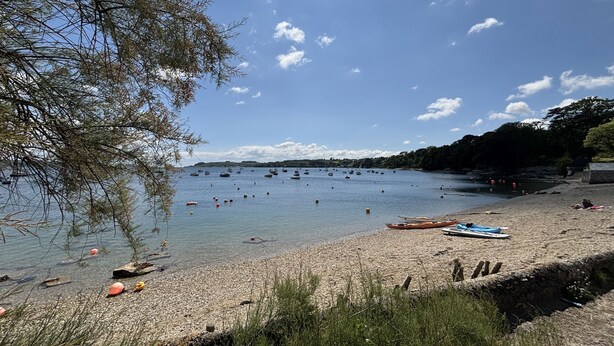 A beach with boats, a clear sky, and a rocky shoreline. - Nanvivian (Truro)
