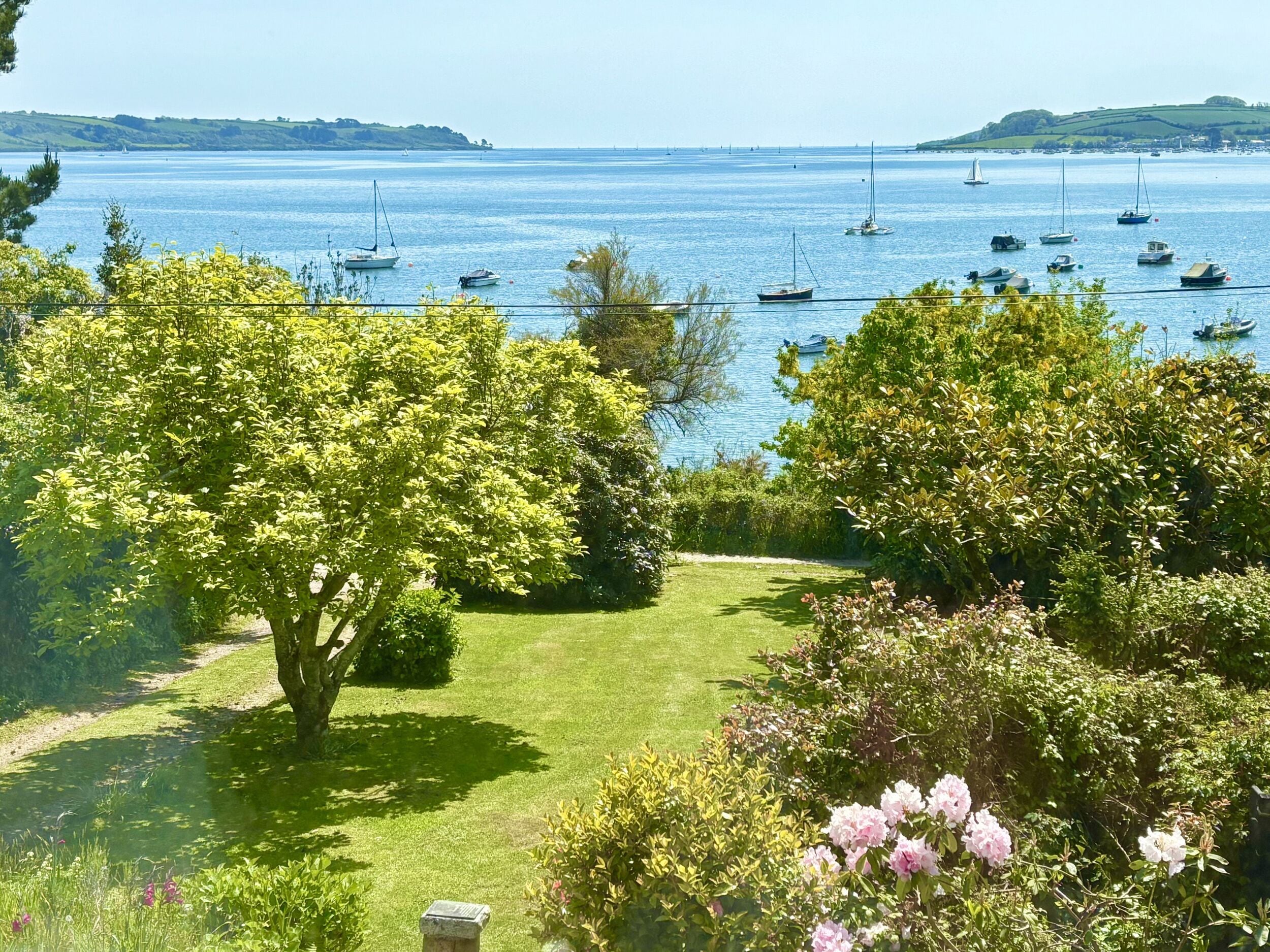 A coastal garden with a view of the sea and boats.