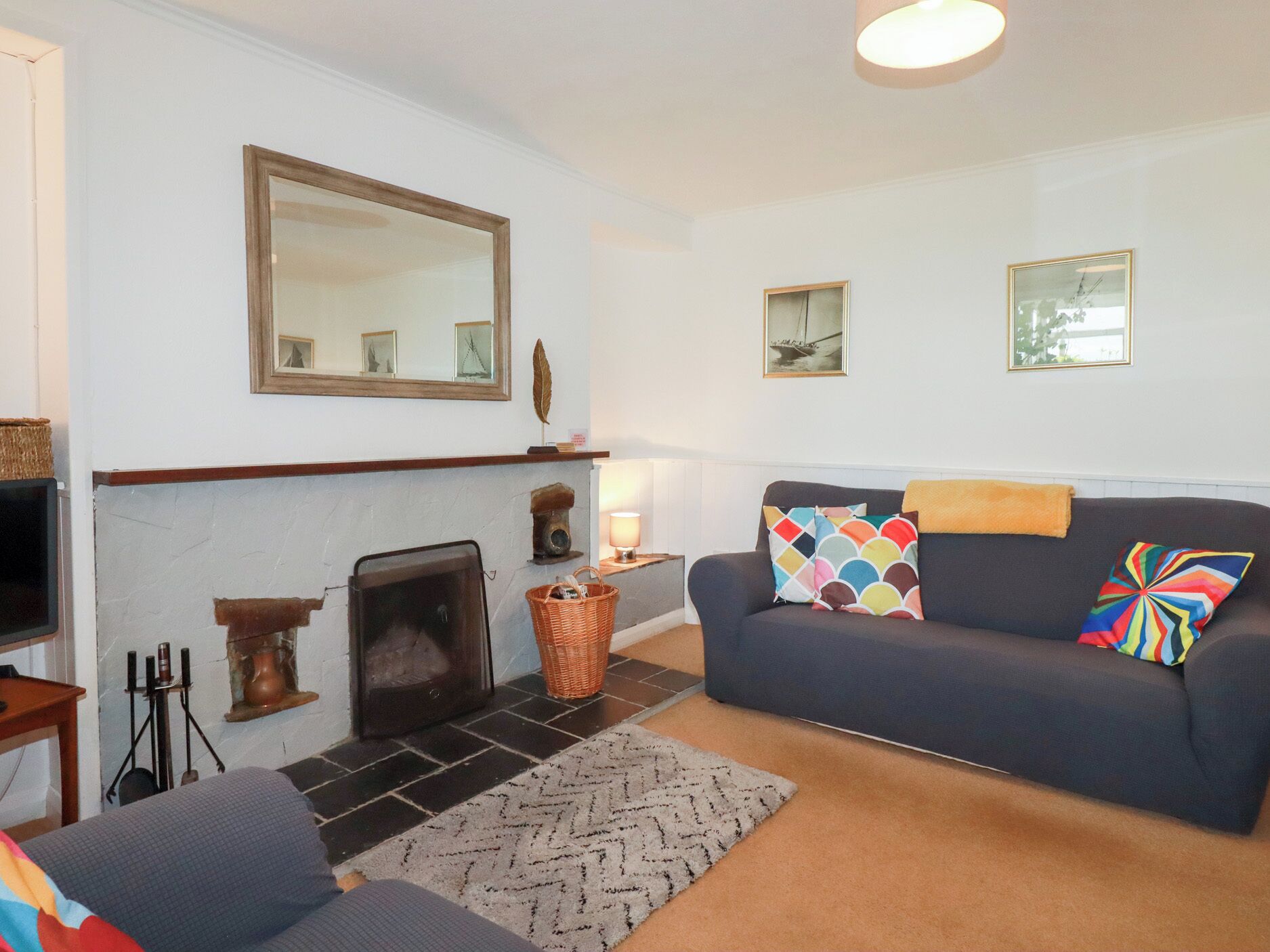 Ein Wohnzimmer mit Kamin, einer Couch, einem gemusterten Teppich und einem Fernseher.