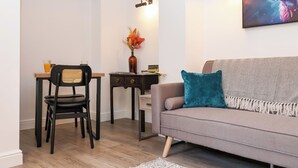 A modern living room with a grey sofa, a black chair, a wooden table, and a small desk.