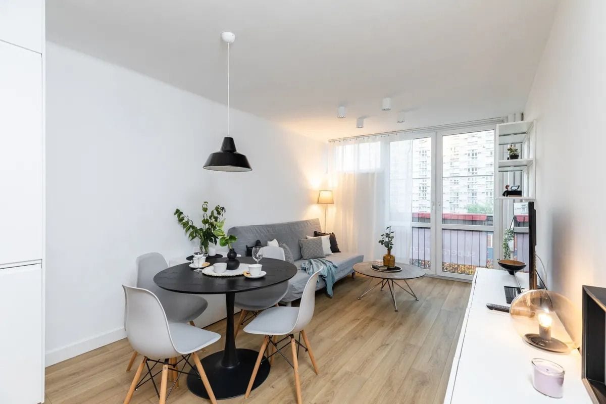 En moderne stue med spisebord, sofa og fjernsyn på et hvidt skab.