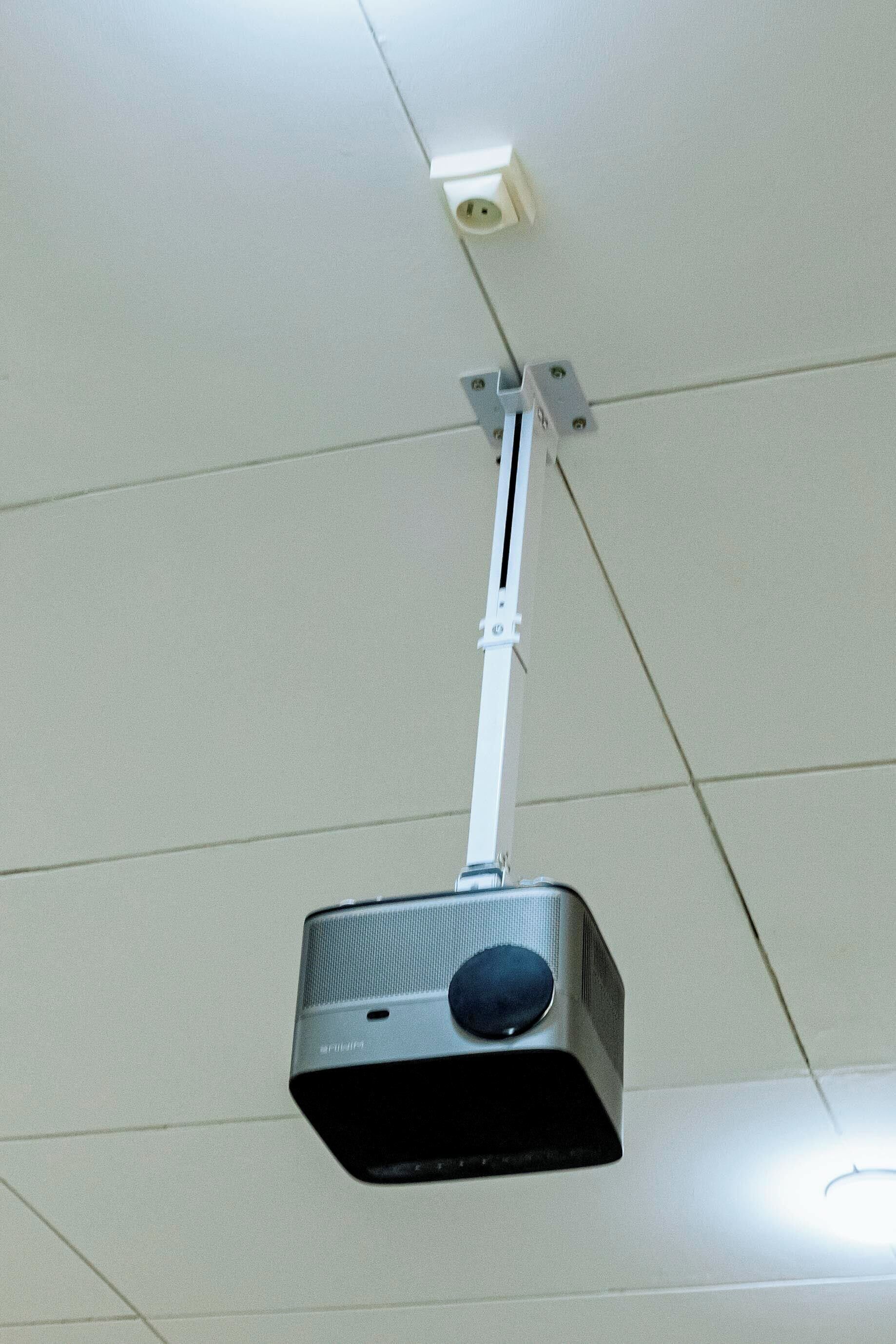 A ceiling-mounted projector with a white cable.