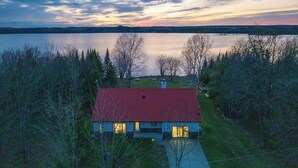 Ein Haus mit rotem Dach, umgeben von Bäumen und einem See.