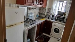 A compact kitchen with a refrigerator, stove, microwave, and washing machine.