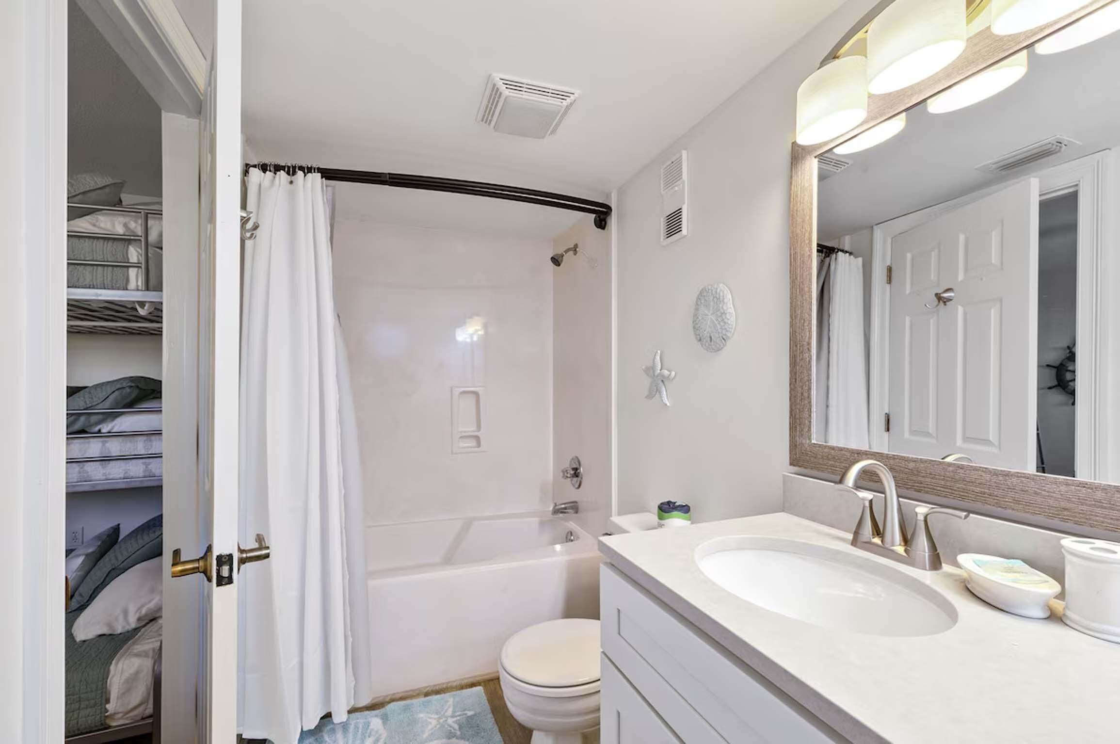 Un bagno con vasca, water e mobile lavabo con lavandino e specchio.