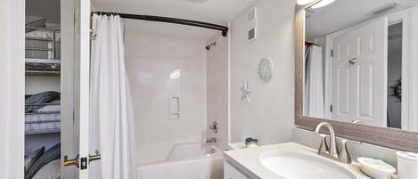 Un bagno con vasca, water e mobile lavabo con lavandino e specchio.