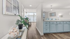 Una cucina moderna con pensili azzurri, un'isola centrale e un'area pranzo con vista sull'esterno.
