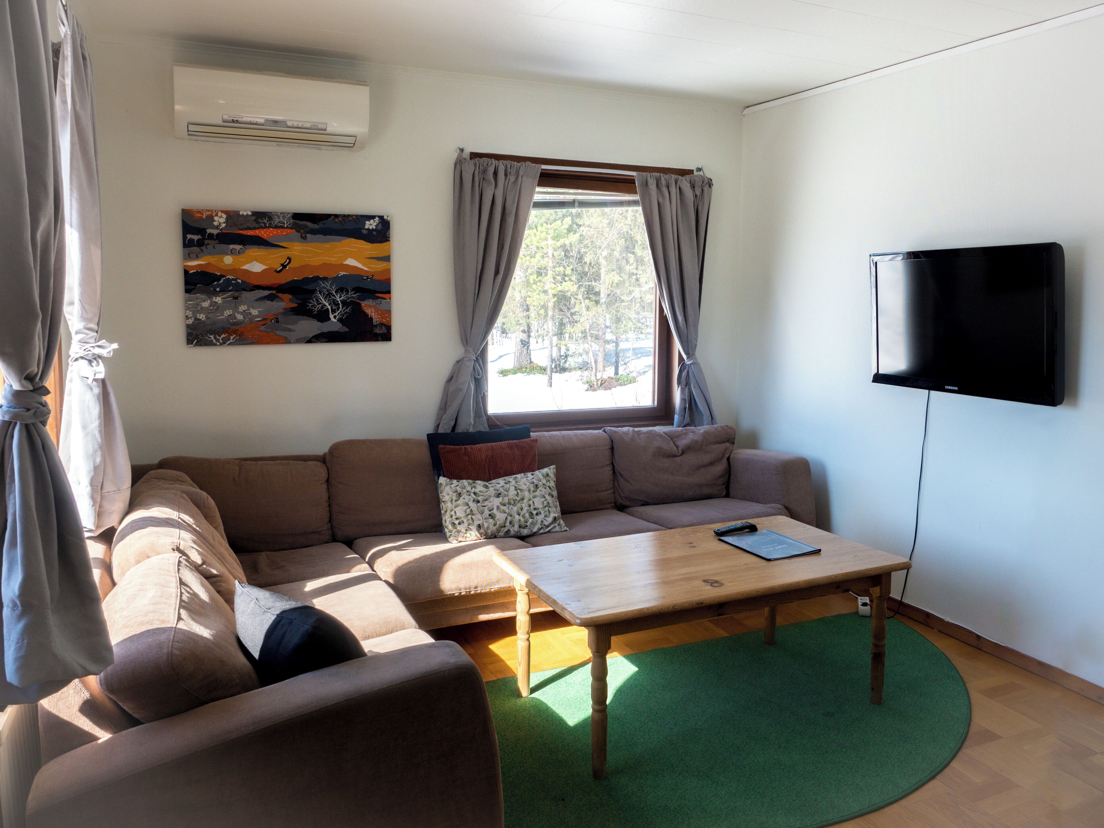 A living room with a sofa, a coffee table, a TV, and a painting on the wall.