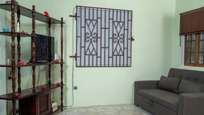 Una sala de estar con un mueble de televisión de madera oscura, un sofá gris y una puerta de metal decorativa en la pared.