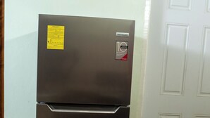 Un refrigerador de acero inoxidable con una etiqueta amarilla, una puerta blanca y baldosas de suelo estampadas.