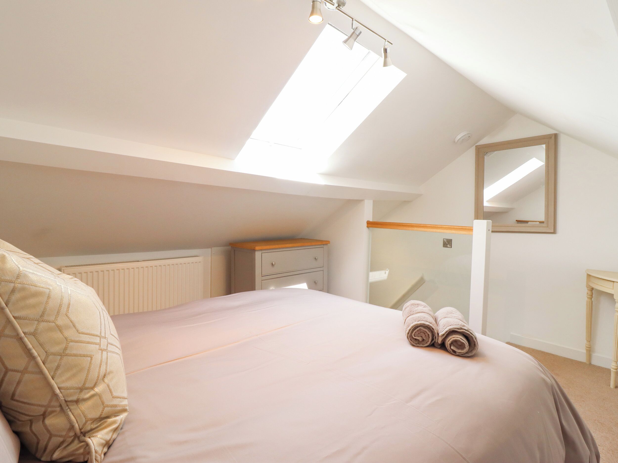 Un dormitorio con cama, mesita de noche, espejo y radiador.