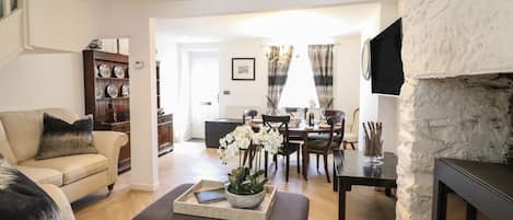 A living room with a sofa, ottoman, and a dining area with a table set for four.