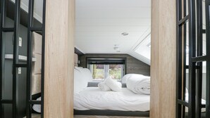A bedroom with a bed, a window, and a herringbone-patterned floor.