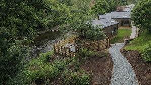 A riverside property with a wooden deck, a pathway, and a house with a grey roof.