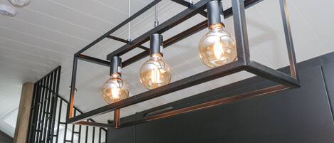 Un lustre moderne composé de trois ampoules en verre suspendues à une armature métallique.
