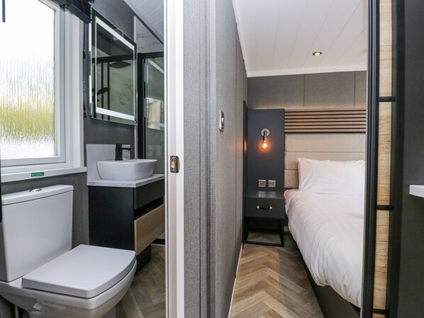 Un baño moderno con inodoro, lavamanos y espejo.