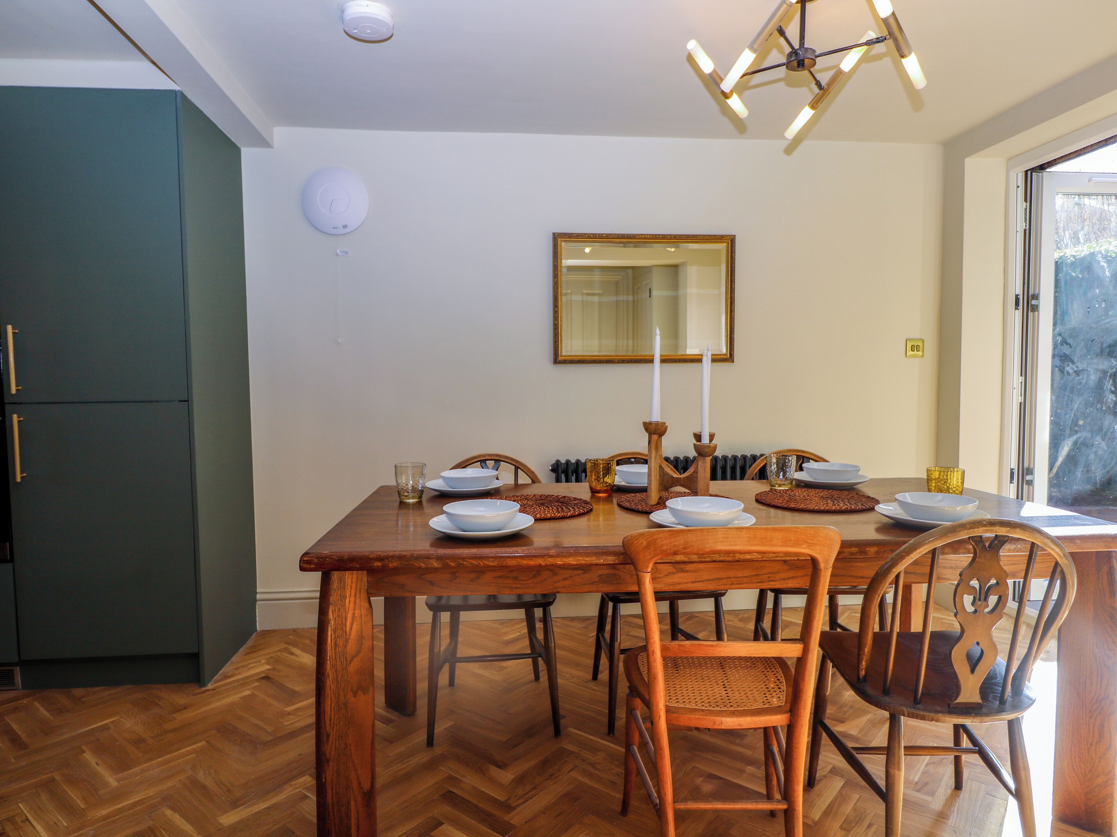 A dining area with a wooden table, chairs, and a mirror above it.