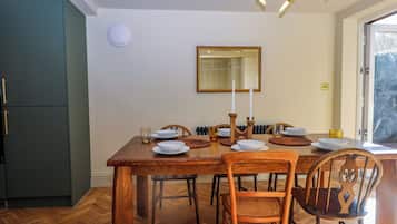 A dining area with a wooden table, chairs, and a mirror above it.