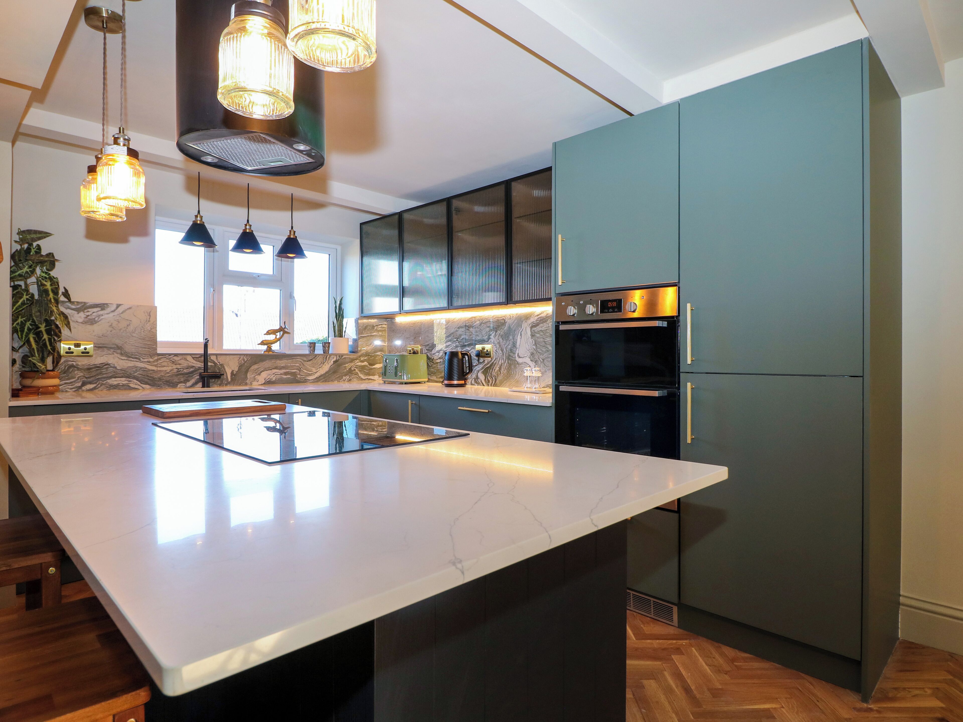 A modern kitchen with a large island, built-in appliances, and pendant lighting.