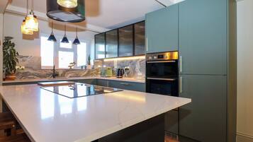 A modern kitchen with a large island, built-in appliances, and pendant lighting.