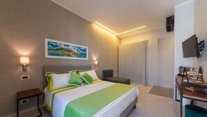 Una habitación de hotel moderna con una cama grande, un escritorio con una silla, un televisor de pantalla plana y un cuadro en la pared.